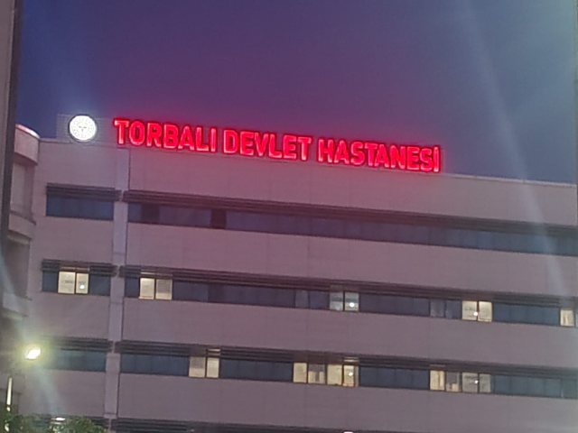 Torbalı Devlet Hastanesi cephesinde kırmızı ışıklı harf tabela, alacakaranlıkta